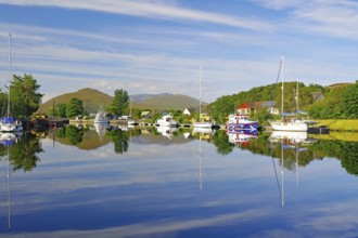 Calm river landscape with anchored boats and clear reflections, Caledonian Canal, Fort William,