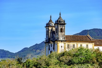 Historic baroque church tower amidst the vegetation and mountains of Ouro Preto
