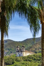 Historic baroque church seen through the trees with the mountains of Ouro Preto city, Ouro Preto,