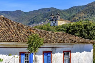 Old weathered colonial house with a baroque church and mountain in the background in the historic