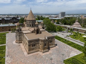 An old church with impressive architecture surrounded by manicured gardens and urban structures,