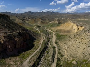 View over a vast desert landscape with mountains and a valley under a cloudy sky, aerial view, on