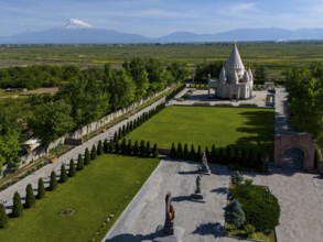 A picturesque landscape with a temple and mountains in the background under a blue sky, aerial