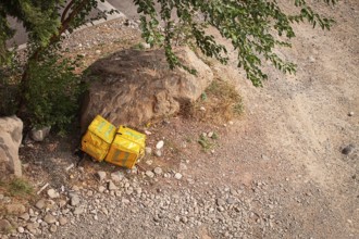 08/25/2025 Georgia, Tbilisi, Delivery packages, Glovo company, left on stony ground, near bushes,
