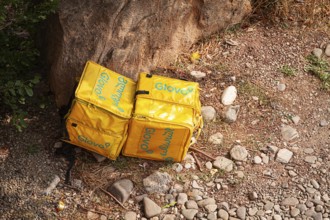 08/25/2025 Georgia, Tbilisi, Delivery packages, Glovo company, left on stony ground, near bushes,