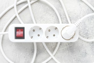 Power strip with multiple sockets and a switch in a cluttered setup on a textured surface during