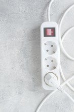 Power strip with multiple sockets and a switch in a cluttered setup on a textured surface during