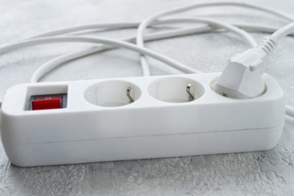 Power strip with multiple sockets and a switch in a cluttered setup on a textured surface during