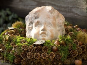 Stone sculpture surrounded by moss, cones and autumnal decoration, Borken, Münsterland, Germany