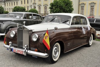 Two-coloured brown and white Rolls-Royce vintage car decorated with flags for a parade, Retro