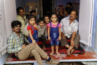 Udaipur, Rajasthan, North India, Asia, family with children sitting in an entrance and smiling