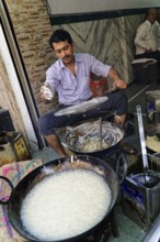Udaipur, Rajasthan, North India, Asia, Man cooking a traditional dish on the street with pans and