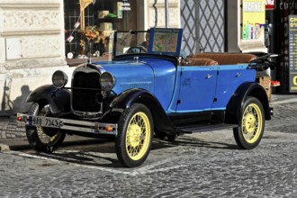 Prague, Czech Republic, Europe, Blue vintage car with yellow wheels parked on the pavement in front