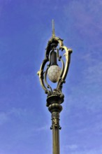 Prague, Czech Republic, Europe, Antique street lamp with ornate decorations in front of a blue sky