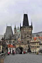 Prague, Czech Republic, Europe, Old stone bridge with imposing towers and buildings in the distance