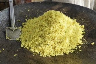 Kota, Rajasthan, North India, Asia, A large pile of poha in an iron pan with a spatula next to it,