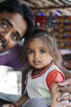 Kota, Rajasthan, North India, Asia, man with little girl, both smiling, in front of a colourful