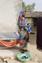 Kota, Rajasthan, North India, Asia, A woman in a colourful garment washes clothes in a rural
