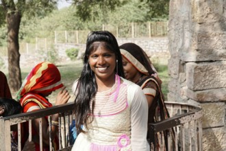 Kota, Rajasthan, North India, Asia, Smiling woman in bright traditional dress in front of a stone
