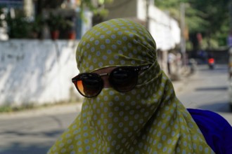 Udaipur, Rajasthan, North India, India, Asia, A woman covered in yellow cloth with sunglasses moves