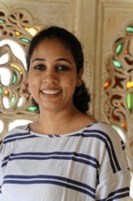 Portrait of a smiling woman in front of ornate, traditional Indian architecture, Udaipur,
