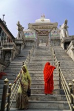 Entrance to Jagdish Temple, Udaipur, people climb the steps to a temple, flanked by statues under a