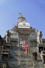 Entrance to Jagdish Temple, Udaipur, People climb the steps to a temple flanked by statues under a