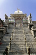 Entrance to Jagdish Temple, Udaipur, People climb the steps to a temple flanked by statues under a