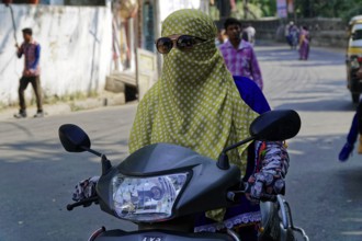 Udaipur, Rajasthan, North India, India, Asia, A veiled woman with sunglasses rides a motorbike on a
