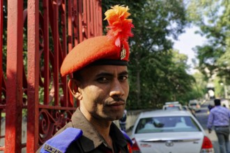 Udaipur, Rajasthan, North India, India, Asia, A guard in uniform with a red beret poses in front of