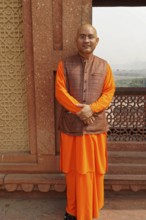 Agra, Uttar Pradesh, India, Asia, A monk in orange-coloured clothes stands in front of a historical