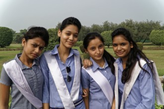 Four girls in uniform standing close together and smiling in a garden, Agra, Jodhpur, Rajasthan,