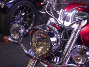 Retro motorbike with shiny chrome headlights and reddish finish, light reflections visible,