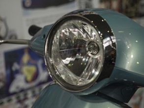 Close-up view of a retro scooter headlight with shiny chrome and a blue housing, dortmund,