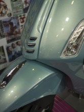 Front of a blue scooter in retro style with glossy paint and shiny chrome details, dortmund,
