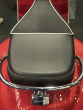 Black motorbike seat with white stitching on red base and chrome handle, dortmund, deutchland