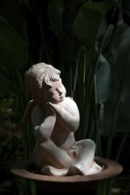 Stone sculpture of a pensive angel in a dark, shady garden, südlohn, westphalia, germany