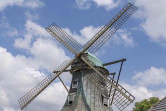 Windmill with open wings in front of a blue sky and decorative clouds, südlohn, westphalia, germany