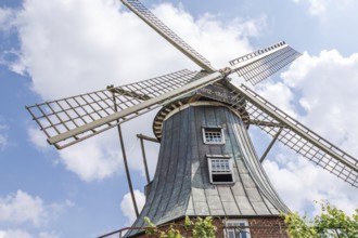 Historic windmill with wooden sails in front of a blue sky and clouds, südlohn, westphalia, germany