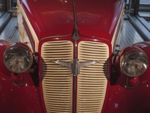 Front view of a red classic car, emphasising the radiator grille and round headlights, Cologne,