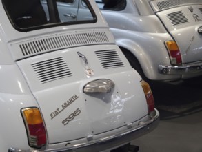 Two white Fiat Abarth vintage cars in an exhibition representing classic automotive history,