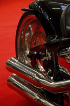 Exhaust system of a black motorbike against a red background, emphasising elegant lines, dortmund,