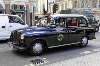 Black taxi driving on a busy London street in daylight, London, London region, England, United