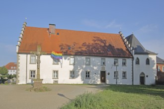 Hospital building built in the 16th century with crucifix and rainbow flag, peace flag, Lower