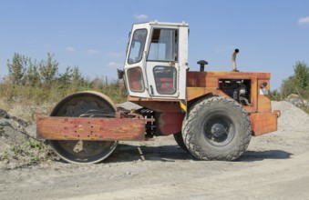 A roller-compactor in sunny illuminated building lot ambiance