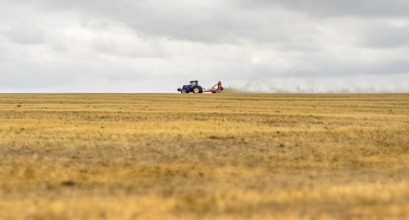 Stormy farmland scenery showing a Tractor on a stubble field in Hohenlohe, an area in Southern
