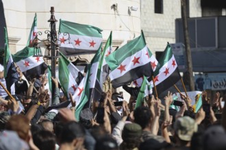 Thousands of Syrians march in Idlib carrying the Syrian revolutionary flag during a protest against
