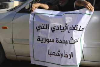 Thousands of Syrians march in Idlib carrying the Syrian revolutionary flag during a protest against