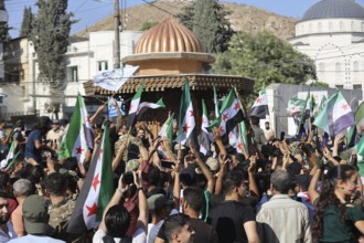 Thousands of Syrians march in Idlib carrying the Syrian revolutionary flag during a protest against