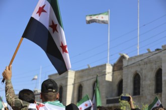 Thousands of Syrians march in Idlib carrying the Syrian revolutionary flag during a protest against